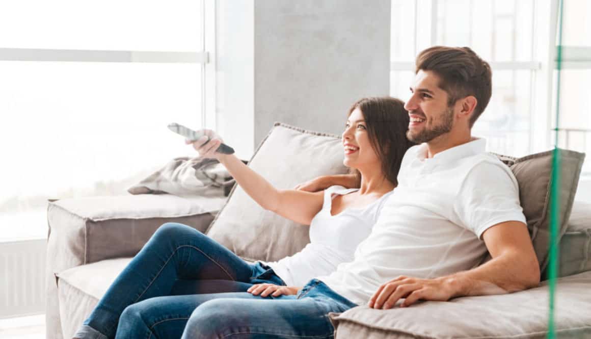 best IPTV happy young couple sitting and watching tv at home